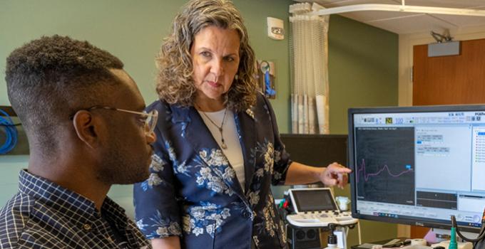 Faculty member working with a medical Resident. Demonstrating how to test a patient with a device connected to a monitor
