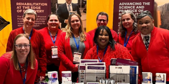 Group of PM&R faculty and staff gathered around a exhibit hall table