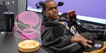 Man in a power wheelchair using assistive technology to complete tasks