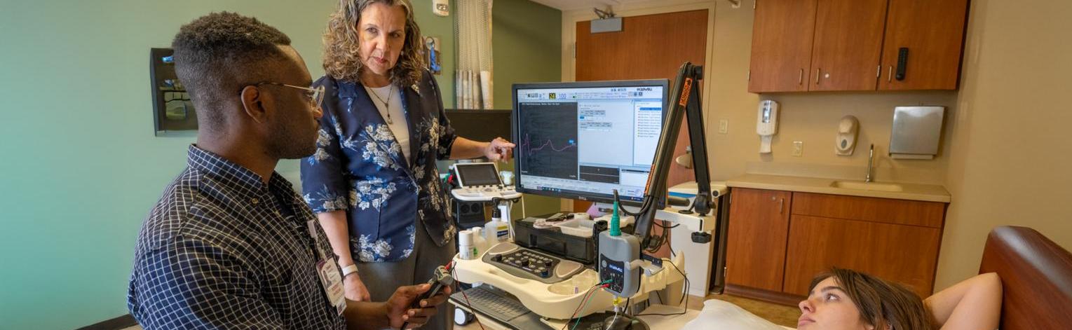 Professor working with a resident, as he uses testing equipment on a patient