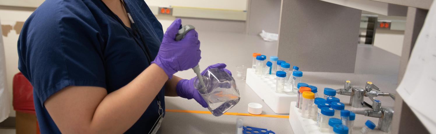 Researcher using a syringe to dispense liquid into a test tube
