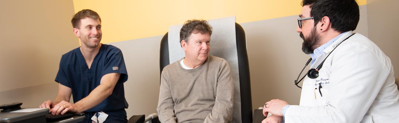 Physician consulting patient with Resident at the computer